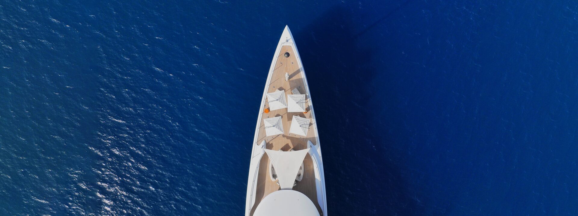 A superyacht under way across deep blue open sea